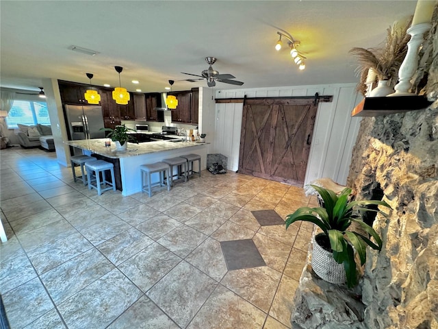 kitchen featuring pendant lighting, stainless steel fridge, dark brown cabinets, a kitchen bar, and kitchen peninsula