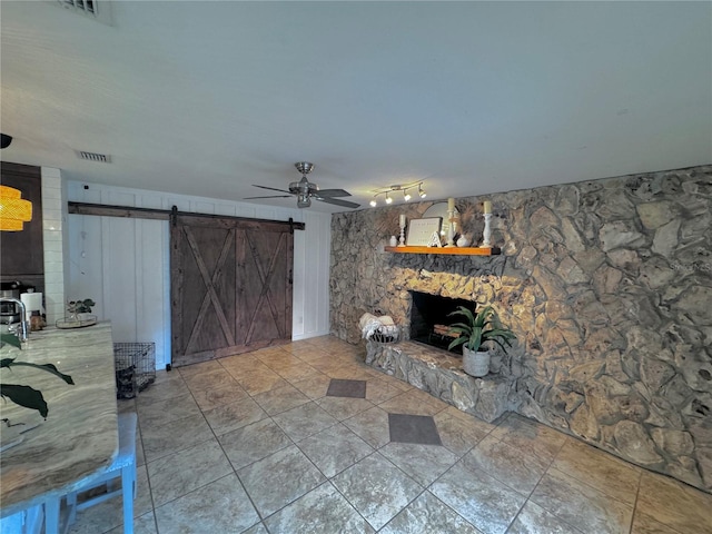 living room with a stone fireplace and ceiling fan