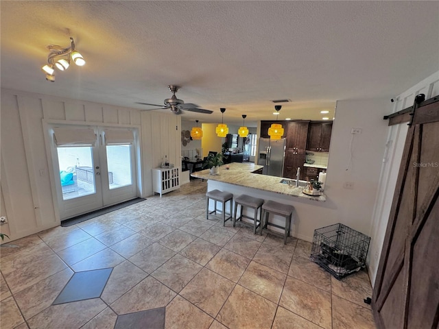 730 NE 18th Ave, Ocala, FL 34470 - kitchen with a sink, a barn door, a kitchen bar, stainless steel fridge with ice dispenser, and dark brown cabinets