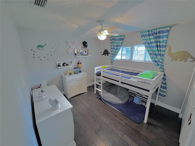 bedroom featuring dark hardwood / wood-style flooring, a textured ceiling, and ceiling fan