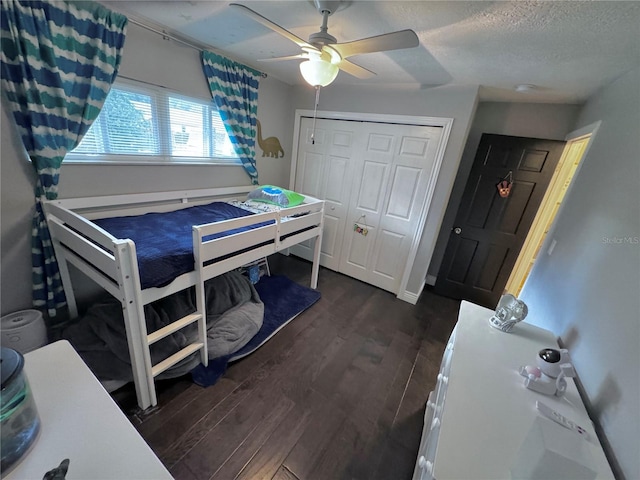 bedroom with ceiling fan, dark hardwood / wood-style floors, a textured ceiling, and a closet