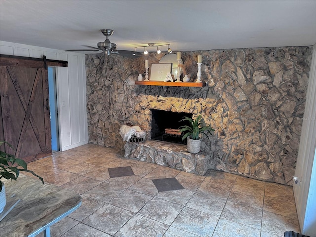 living room featuring ceiling fan, a barn door, and a fireplace