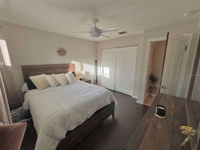 bedroom with ceiling fan, dark parquet floors, and a closet