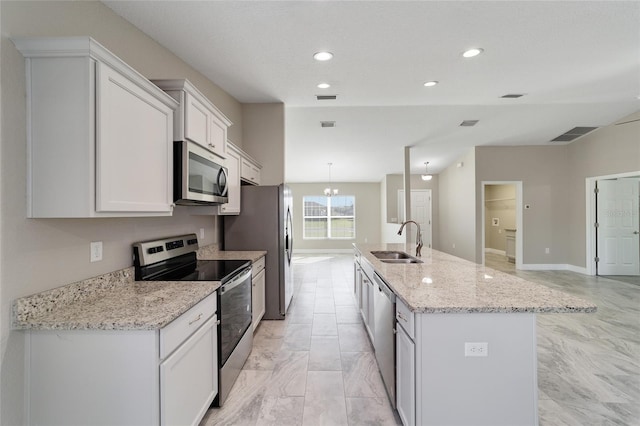 kitchen with light stone counters, an island with sink, appliances with stainless steel finishes, white cabinetry, and sink