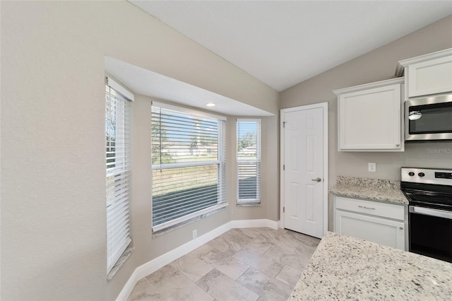 kitchen featuring white cabinetry, stainless steel appliances, light stone countertops, and vaulted ceiling