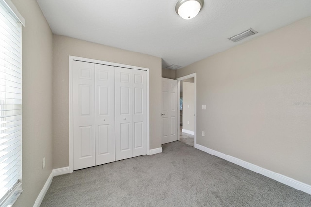 unfurnished bedroom with a closet and light carpet