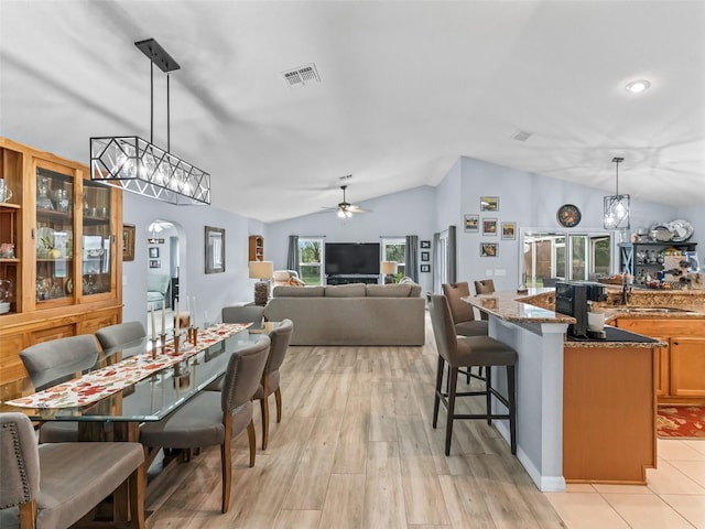 dining room with ceiling fan, sink, lofted ceiling, and light wood-type flooring