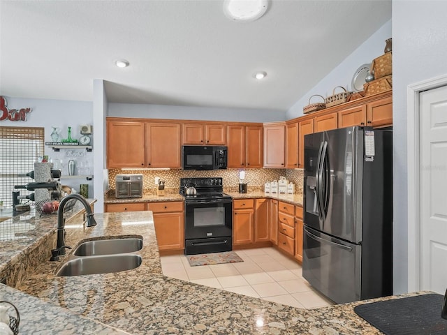 kitchen with light stone countertops, sink, lofted ceiling, and black appliances