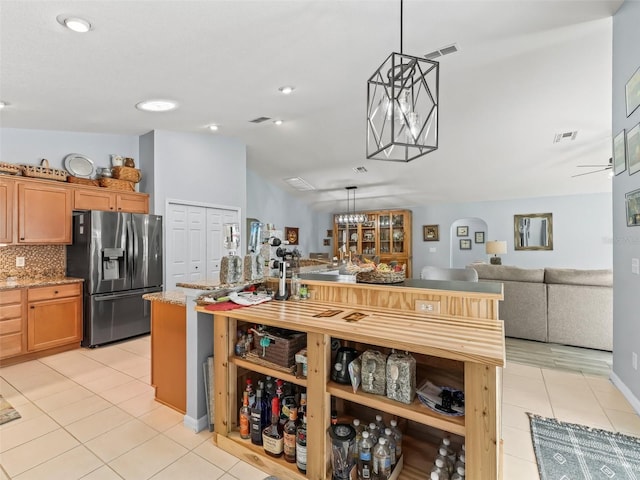 kitchen with stainless steel refrigerator with ice dispenser, light stone counters, pendant lighting, and light tile patterned flooring