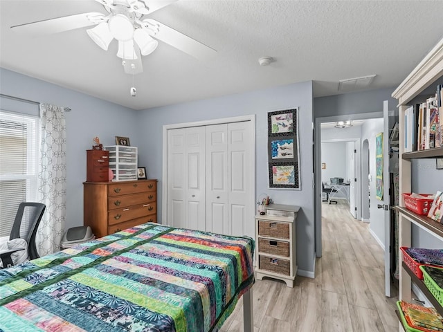 bedroom with a textured ceiling, a closet, ceiling fan, and light hardwood / wood-style floors