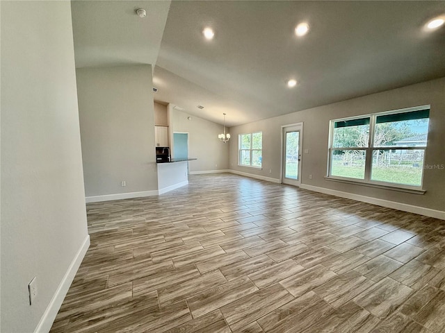 unfurnished living room with light wood-style flooring, recessed lighting, baseboards, vaulted ceiling, and an inviting chandelier