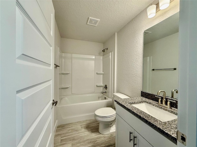 bathroom featuring visible vents, a textured wall, a textured ceiling, and wood finished floors