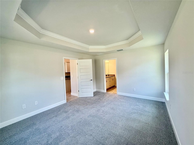 unfurnished bedroom with carpet floors, a raised ceiling, visible vents, ornamental molding, and baseboards