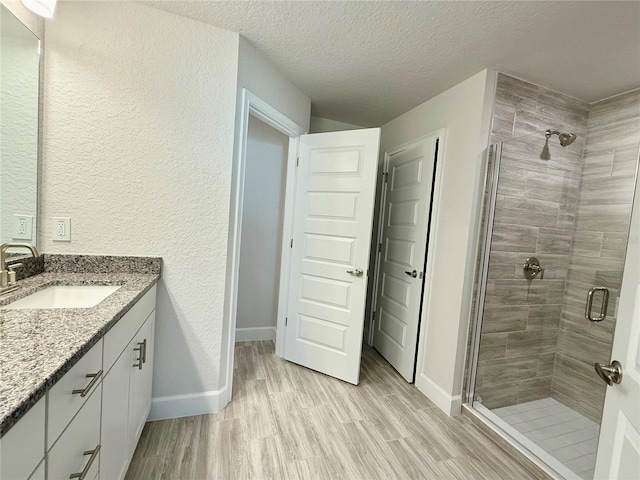 full bath with wood finished floors, a shower stall, vanity, and baseboards