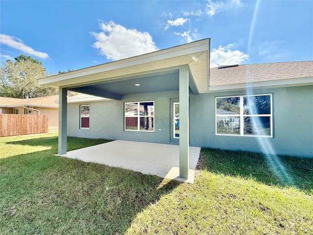 back of house with a yard, a patio area, fence, and stucco siding