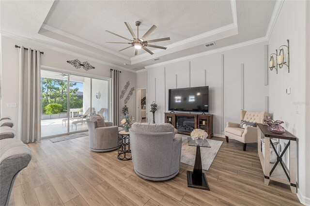 living room featuring crown molding, hardwood / wood-style floors, ceiling fan, and a raised ceiling