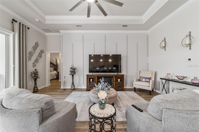 living room with a tray ceiling, ceiling fan, and crown molding