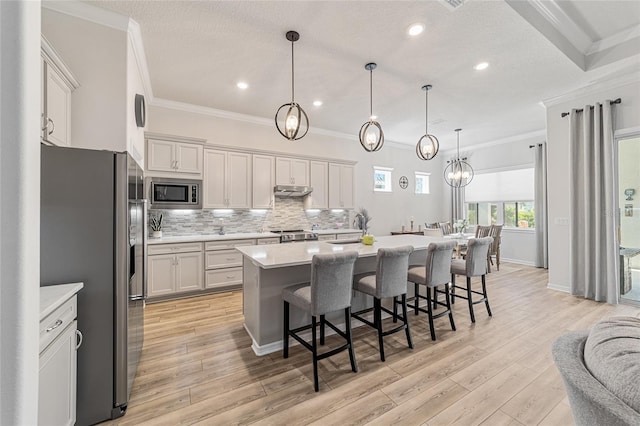 kitchen featuring light hardwood / wood-style flooring, ornamental molding, and stainless steel appliances