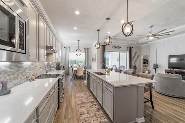 kitchen with sink, appliances with stainless steel finishes, a breakfast bar area, hanging light fixtures, and wood-type flooring