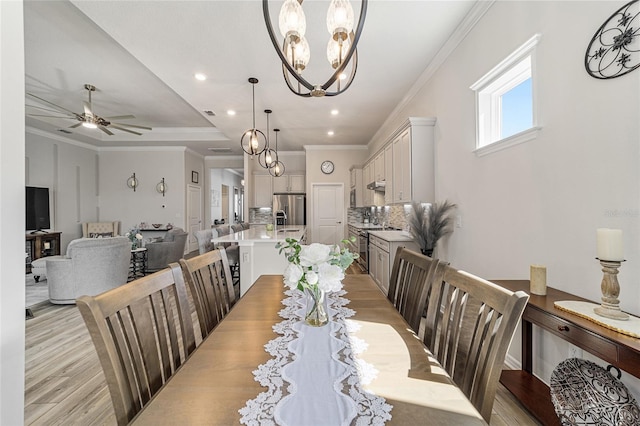 dining room with ceiling fan with notable chandelier, light hardwood / wood-style floors, and crown molding