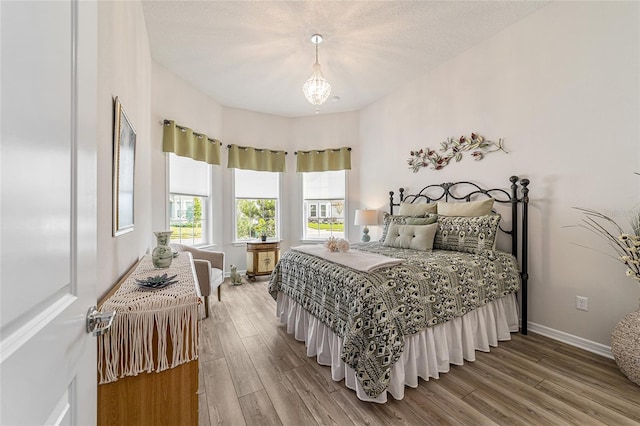 bedroom featuring an inviting chandelier, hardwood / wood-style floors, and a textured ceiling