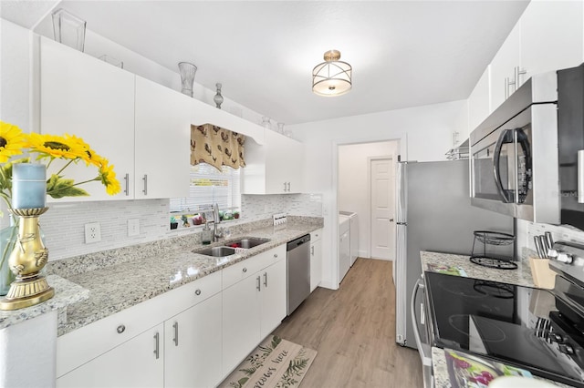 kitchen with appliances with stainless steel finishes, light hardwood / wood-style floors, white cabinetry, and sink