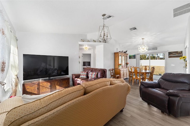 living room with light hardwood / wood-style floors and a notable chandelier