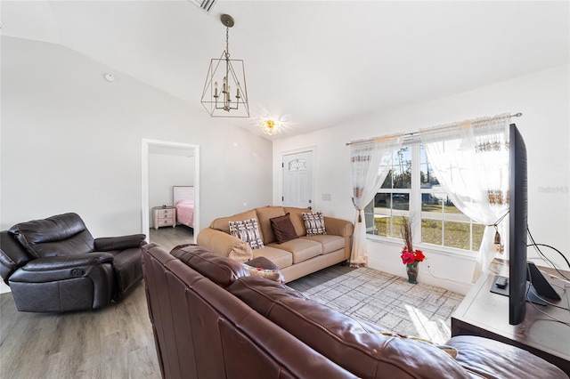 living room featuring hardwood / wood-style flooring, a notable chandelier, and lofted ceiling