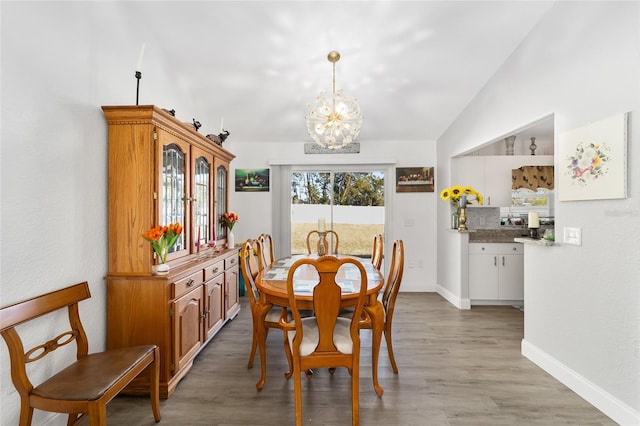 dining area featuring light hardwood / wood-style flooring, lofted ceiling, and a notable chandelier