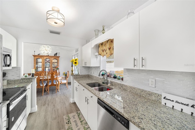 kitchen featuring white cabinets, sink, light hardwood / wood-style flooring, light stone counters, and stainless steel appliances