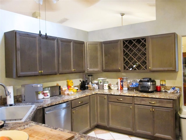 kitchen with light tile patterned floors, sink, stainless steel dishwasher, and light stone counters