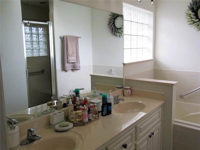 bathroom with vanity, independent shower and bath, and a wealth of natural light