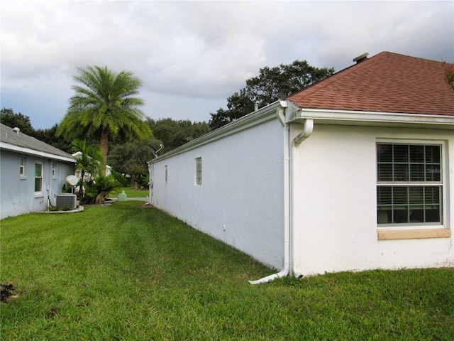 view of side of home with central AC and a lawn