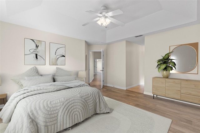 bedroom featuring hardwood / wood-style flooring, ceiling fan, and a tray ceiling