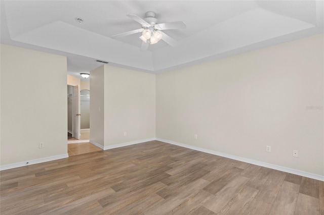 spare room featuring hardwood / wood-style floors, ceiling fan, and a tray ceiling