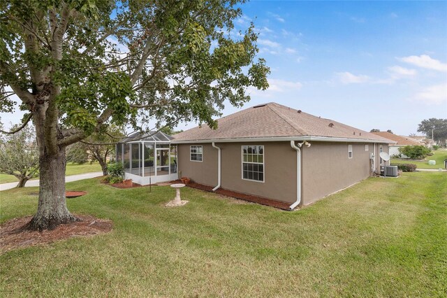 rear view of house featuring cooling unit, a yard, and a lanai