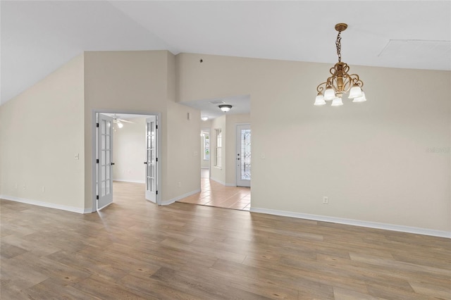 unfurnished room with a notable chandelier, high vaulted ceiling, and light hardwood / wood-style flooring