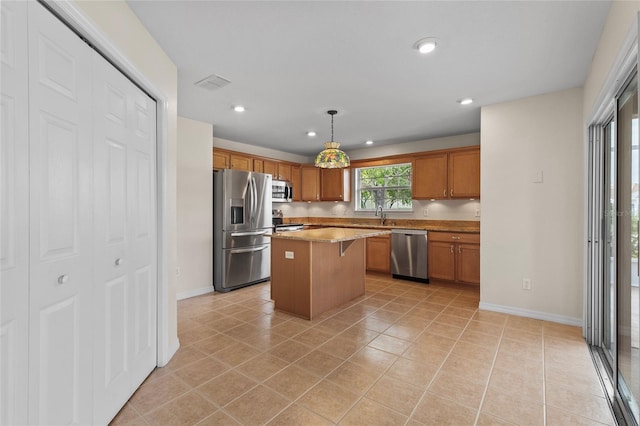 kitchen with a kitchen island, sink, hanging light fixtures, light tile patterned floors, and stainless steel appliances