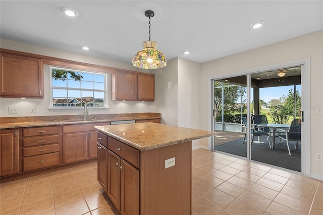 kitchen with a kitchen island, pendant lighting, sink, light tile patterned floors, and light stone countertops