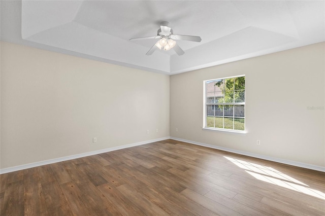 empty room featuring hardwood / wood-style floors, a raised ceiling, and ceiling fan