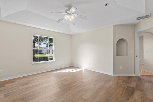 unfurnished room featuring ceiling fan, a tray ceiling, and light wood-type flooring