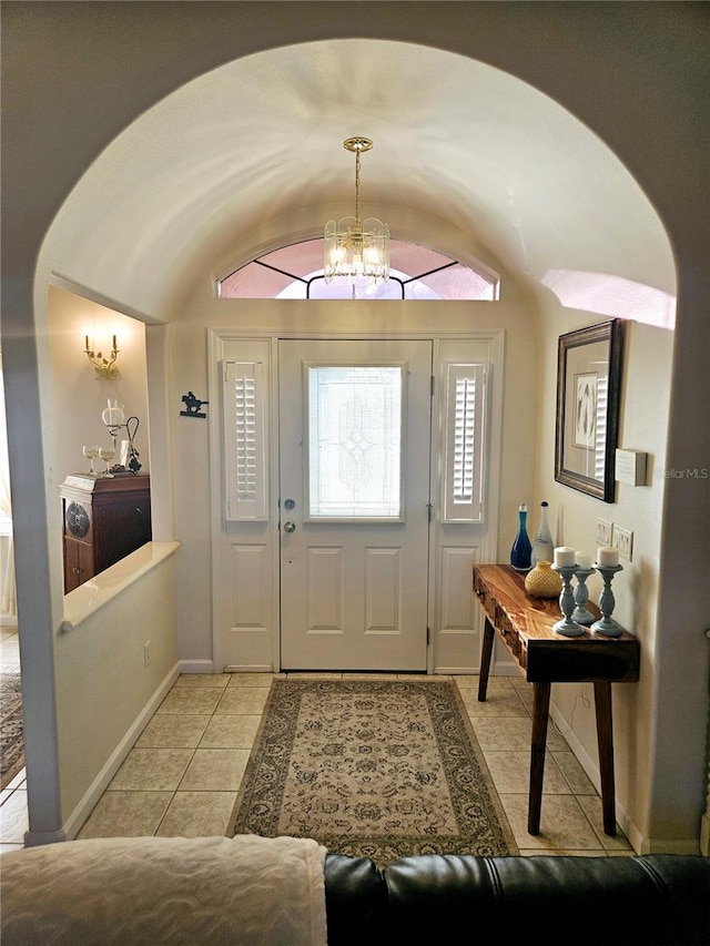 foyer entrance with light tile patterned flooring, vaulted ceiling, and a chandelier