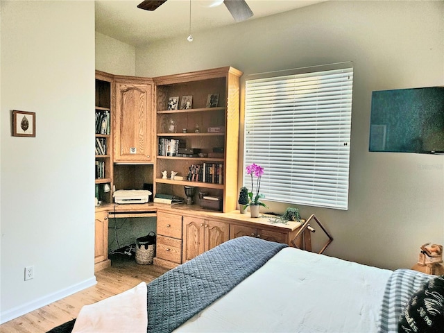 bedroom featuring built in desk, light wood-type flooring, and ceiling fan