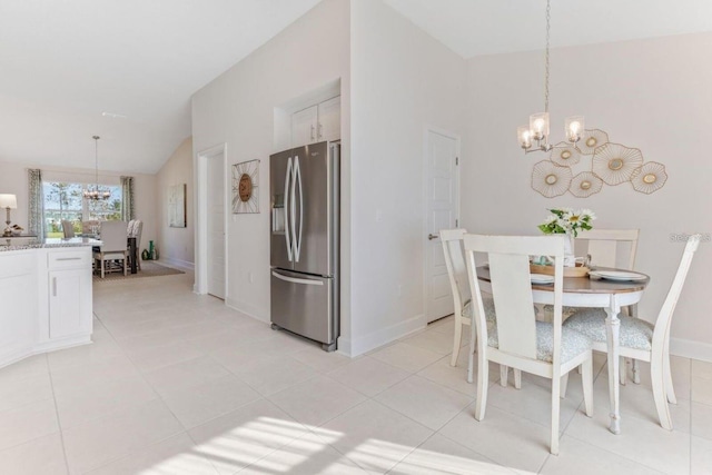 dining room with a notable chandelier, vaulted ceiling, and light tile patterned flooring