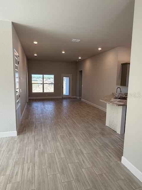 unfurnished living room with light hardwood / wood-style flooring and sink