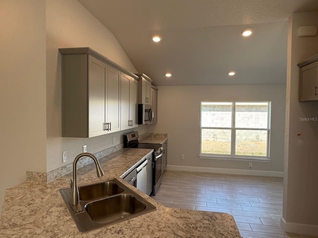 kitchen with vaulted ceiling, sink, stainless steel appliances, gray cabinets, and light stone countertops