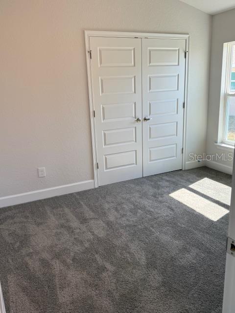 spare room featuring dark carpet and vaulted ceiling