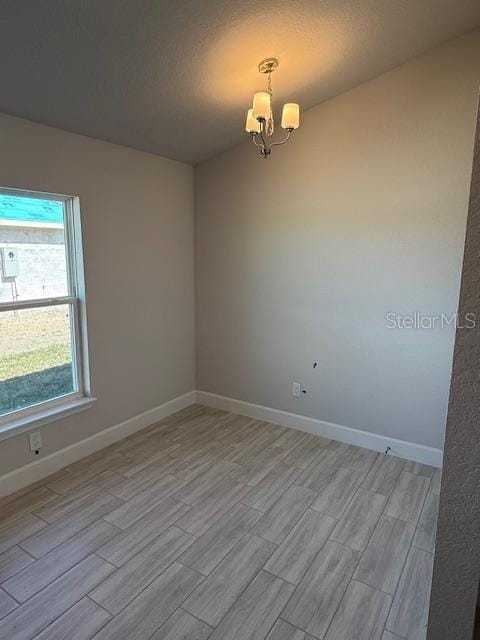 spare room featuring a chandelier and a textured ceiling