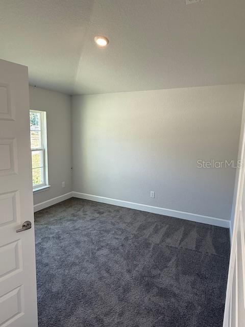 unfurnished room featuring dark colored carpet