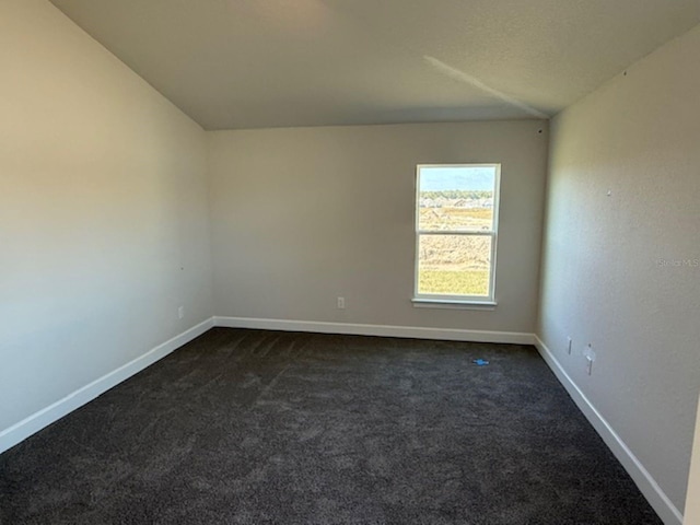 empty room with dark carpet and lofted ceiling